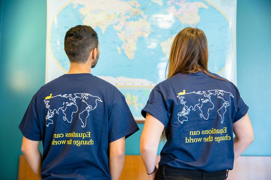 Two people looking at a map. They are wearing t-shirts that say, Equations can change the world.