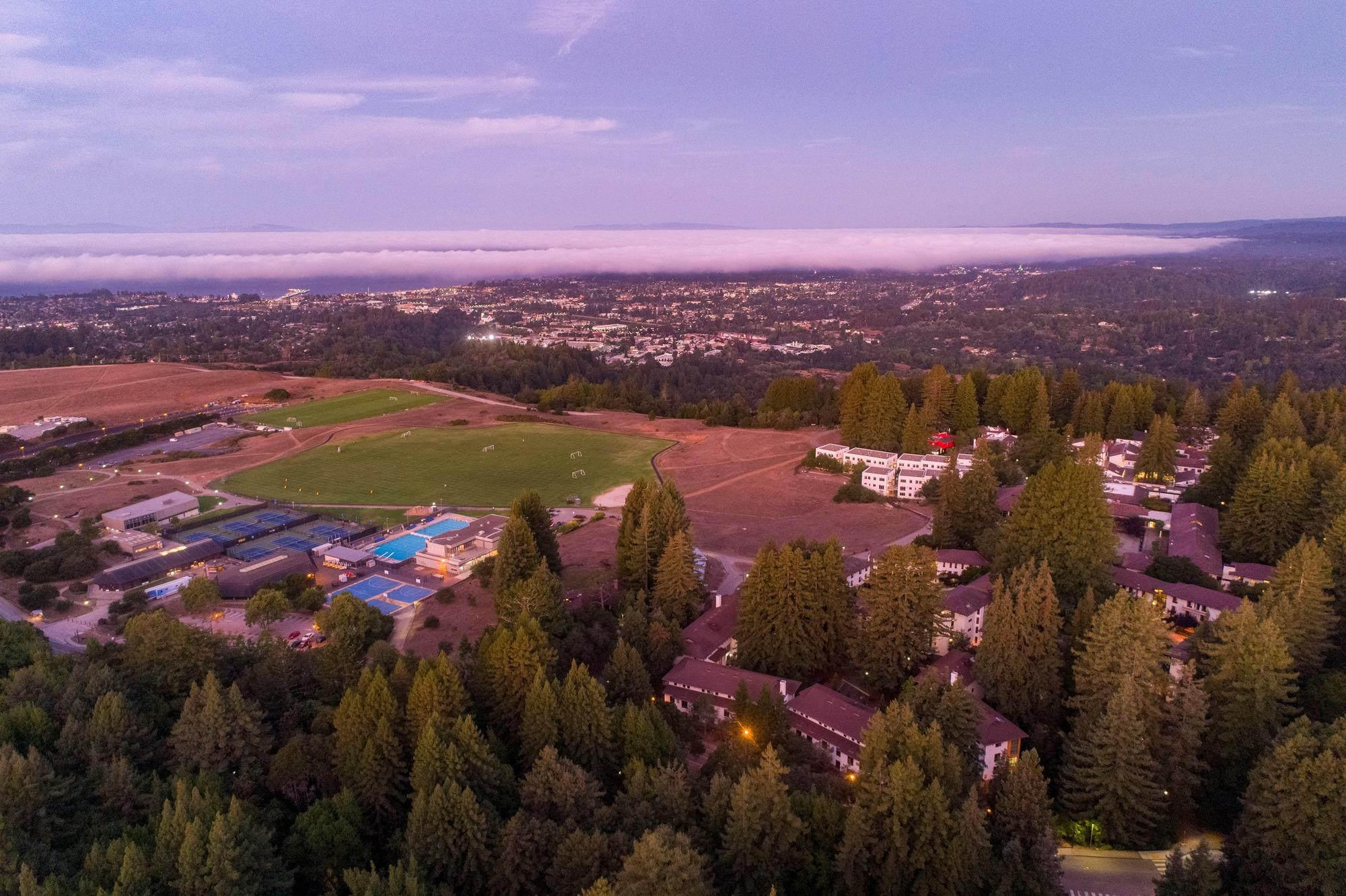 Aerial shot of campus at sunset with Santa Cruz city in  the background.